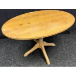 A Pitch pine oval top dining table. Single pedestal support with four outswept legs. [74x122x76cm]