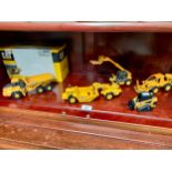 A shelf of die cast cat & Deere vehicles etc