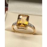 10ct yellow gold ladies ring set with orange cut stone off set by White topaz stone shoulders. [Ring