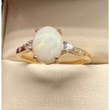 10ct yellow gold ladies ring set with an white opal stone off set by White Spinel stones. [Ring size