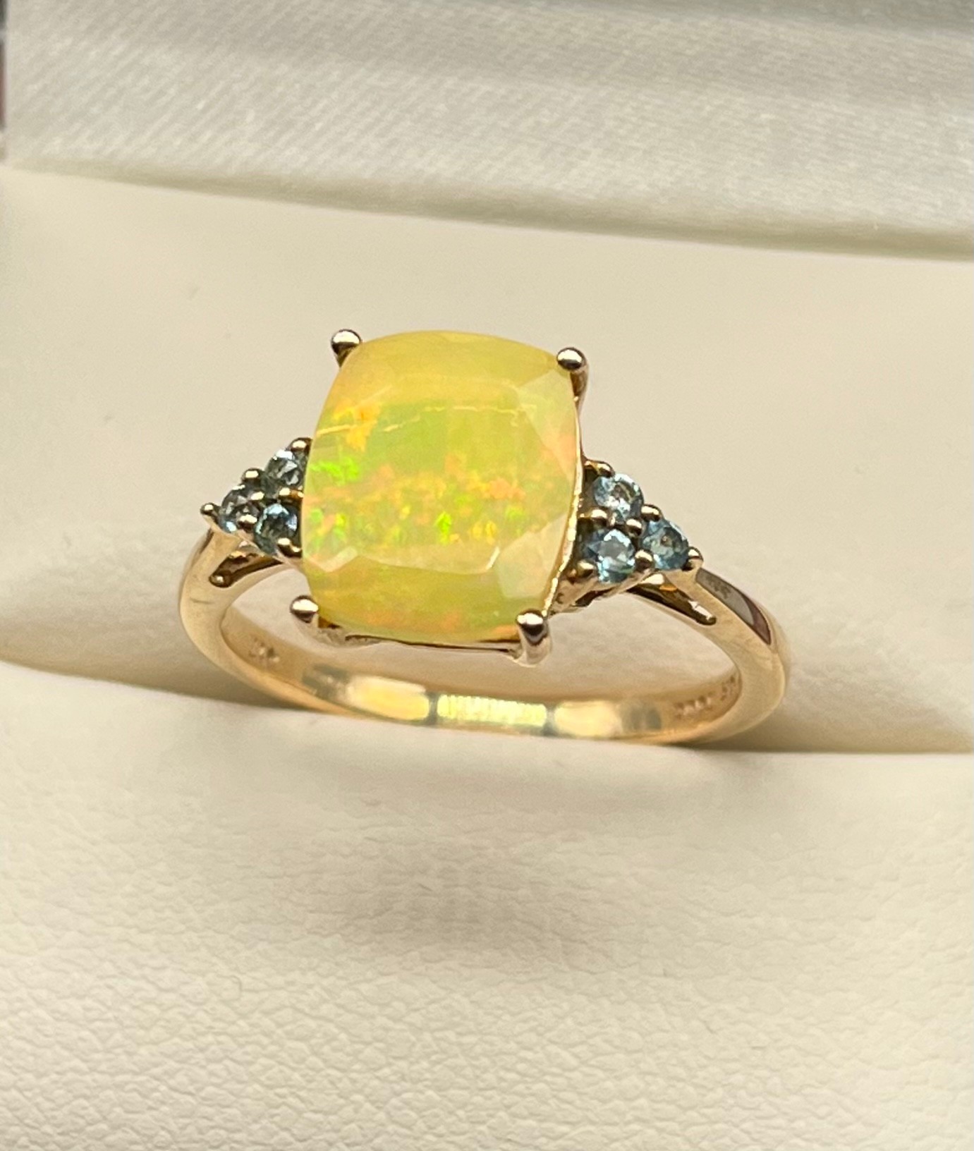 10ct yellow gold ladies ring set with an Ethiopian opal stone off set by blue cut stone