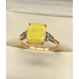 10ct yellow gold ladies ring set with an Ethiopian opal stone off set by blue cut stone