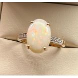 14ct yellow gold ladies ring set with a large opal stone off set by diamond shoulders. [Ring size R]