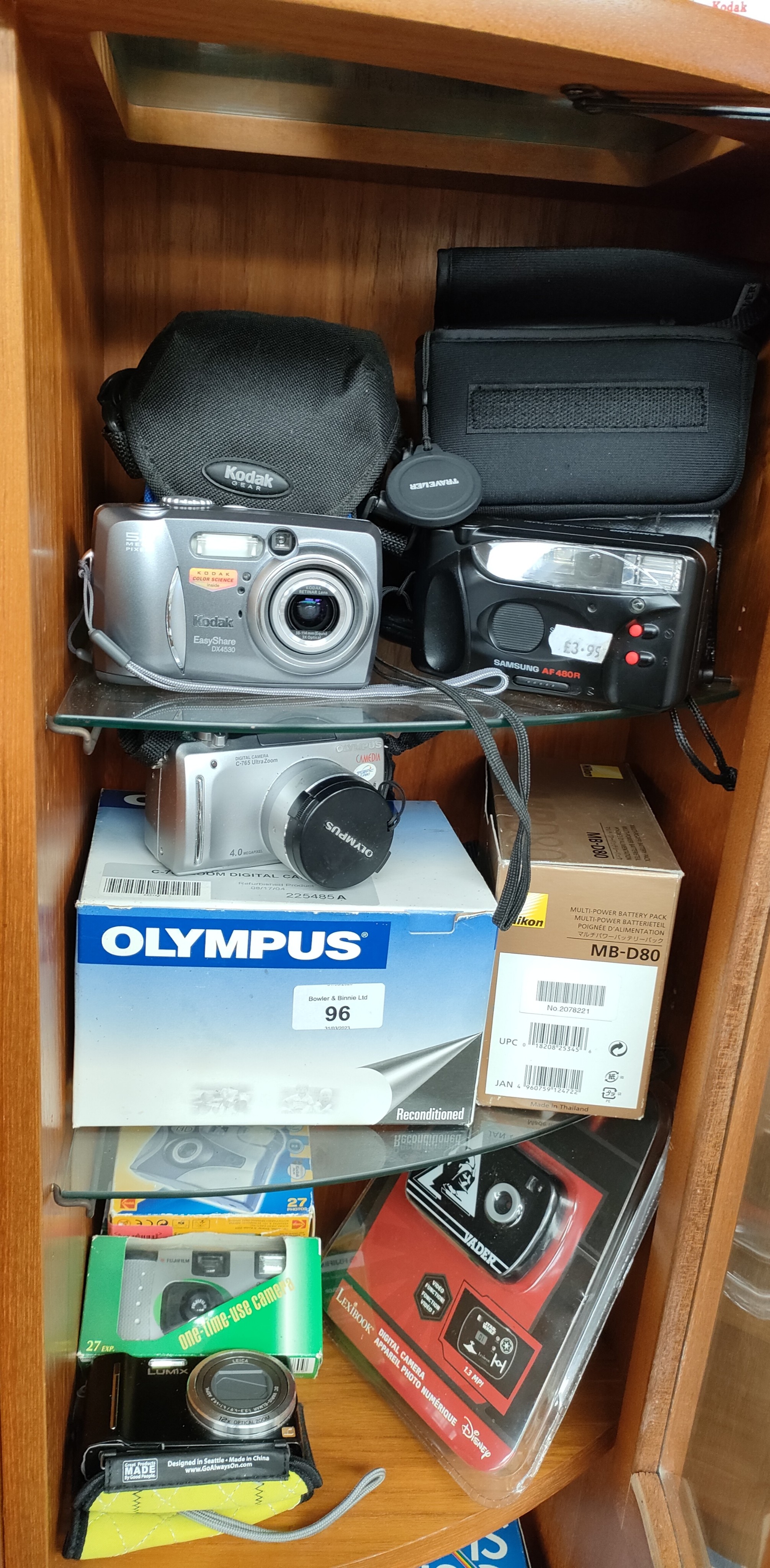 3 Shelves of modern cameras includes Olympus digital c765 ultra zoom, Kodak camera etc