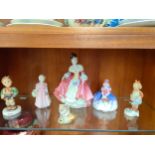 Shelf of Royal Doulton and Hummel figures.
