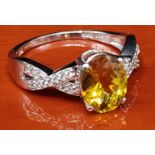 10ct white gold ring set with a citrine style stone off set by white spinel stone shoulders. [Ring