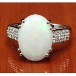 10ct white gold ring set with a large white Australian opal stone off set by white spinel stones [