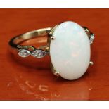 10ct yellow gold ring set with a large Australian white opal stone off set by white spinel stone
