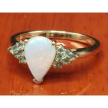10ct yellow gold ladies ring set with a single pear shaped white opal off set by green stones to