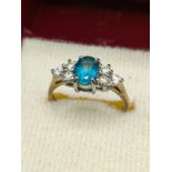 9ct yellow gold ring set with a blue topaz stone off set by white stone shoulders. [Ring size M] [