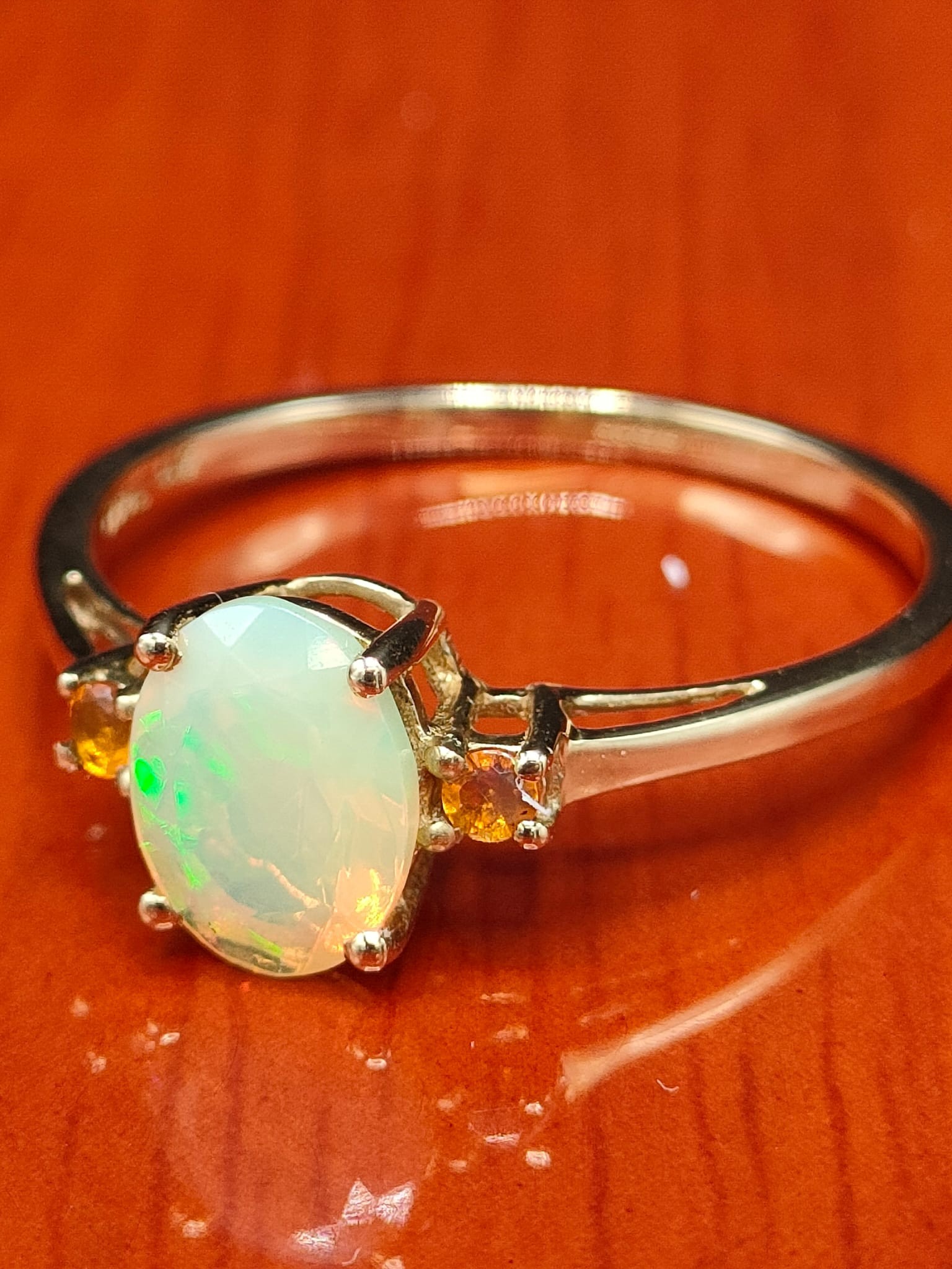 10ct yellow gold ring set with an Ethiopian opal stone off set by two orange stones. [Ring size