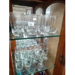 Two shelves of crystal to include Swedish Kosta Boda glass goblets, whiskey and sherry glass