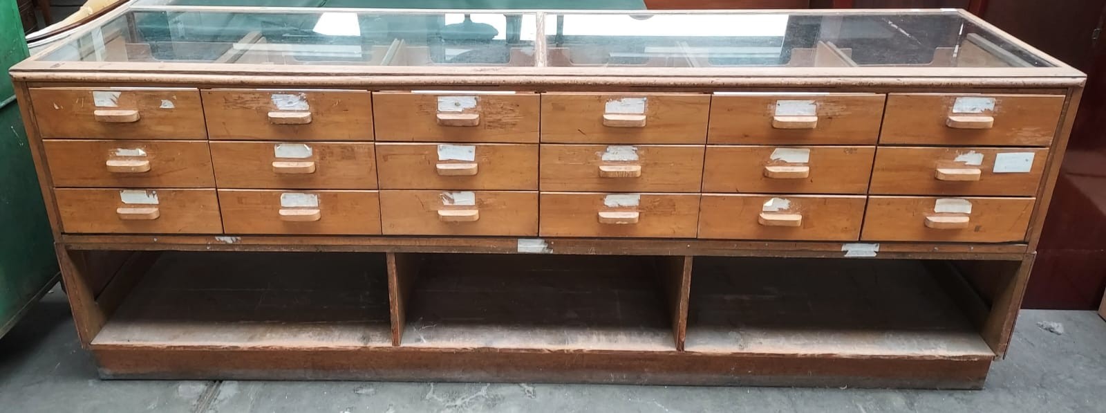 Retro haberdashery shop counter, glazed top and sides above banks of drawers and underneath interior