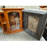 A Small cabinet includes carved figures along with wooden carved sculpture framed