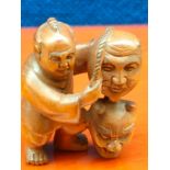 Japanese hand carved root wood netsuke of Oni Mask Seller. Signed to the foot. [4.5cm high]