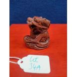 Japanese hand carved root wood netsuke of a Dragon holding a sphere. Fitted with black bead eyes,