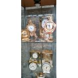 Two shelves of mixed vintage mantel clocks.