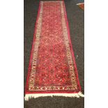 Indian red ground wool runner rug. [290x81cm]