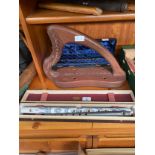 A shelf of wooden carved flutes, boxed musical instruments and an Irish harp