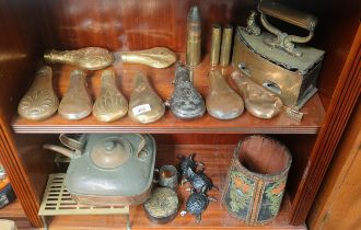 Two shelves of collectables; various antique copper and metal worked gun powder flasks, Brass coal