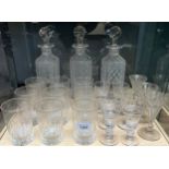 A Shelf of antique crystal; Three decanters, 9 etched and facet cut drinking glasses, a various