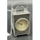 London silver hammer worked travel clock; Has ornate handle, Enamelled face, Supported on bun