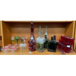 Shelf of antique and vintage art glass; Facet cut ruby glass decanter with stopper, Four green