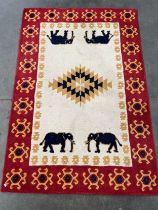 Wool rug of Neutral ground with a red border; designed with four elephant figures. [177x121cm]