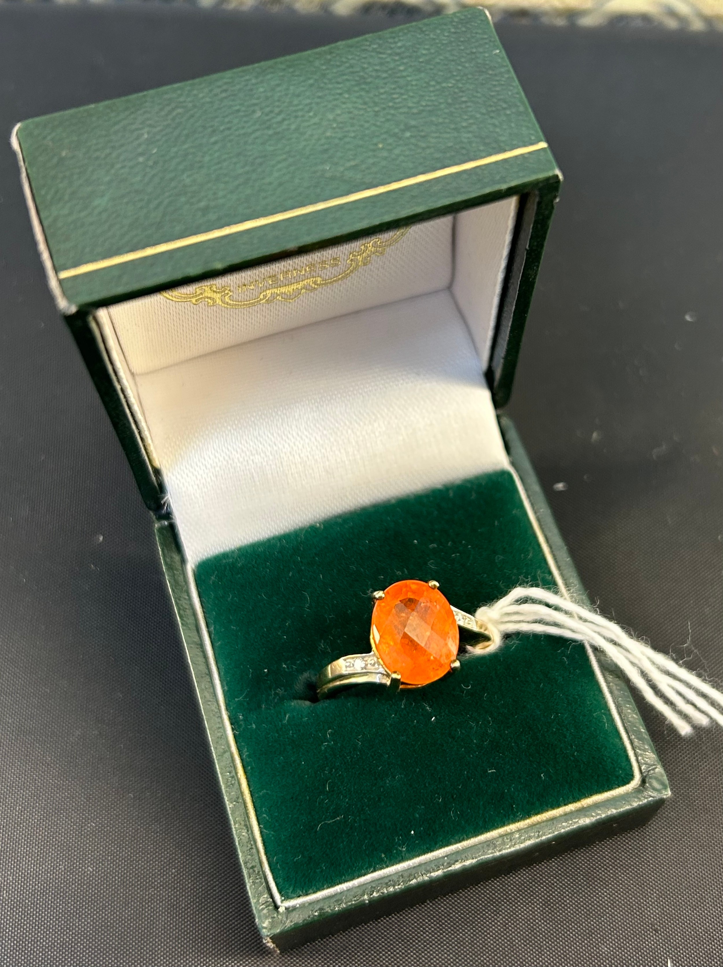9ct yellow gold ladies ring set with orange gem stone off set by diamond shoulders. [Ring size N] [