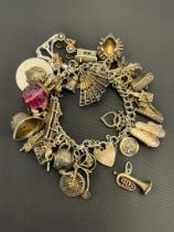 Antique and heavy silver charm bracelet and charms, approximately 30 charms. [96.38grams]