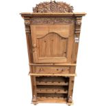 Pine wine unit, a cupboard door and rack surmounted by carved foliate and grape design