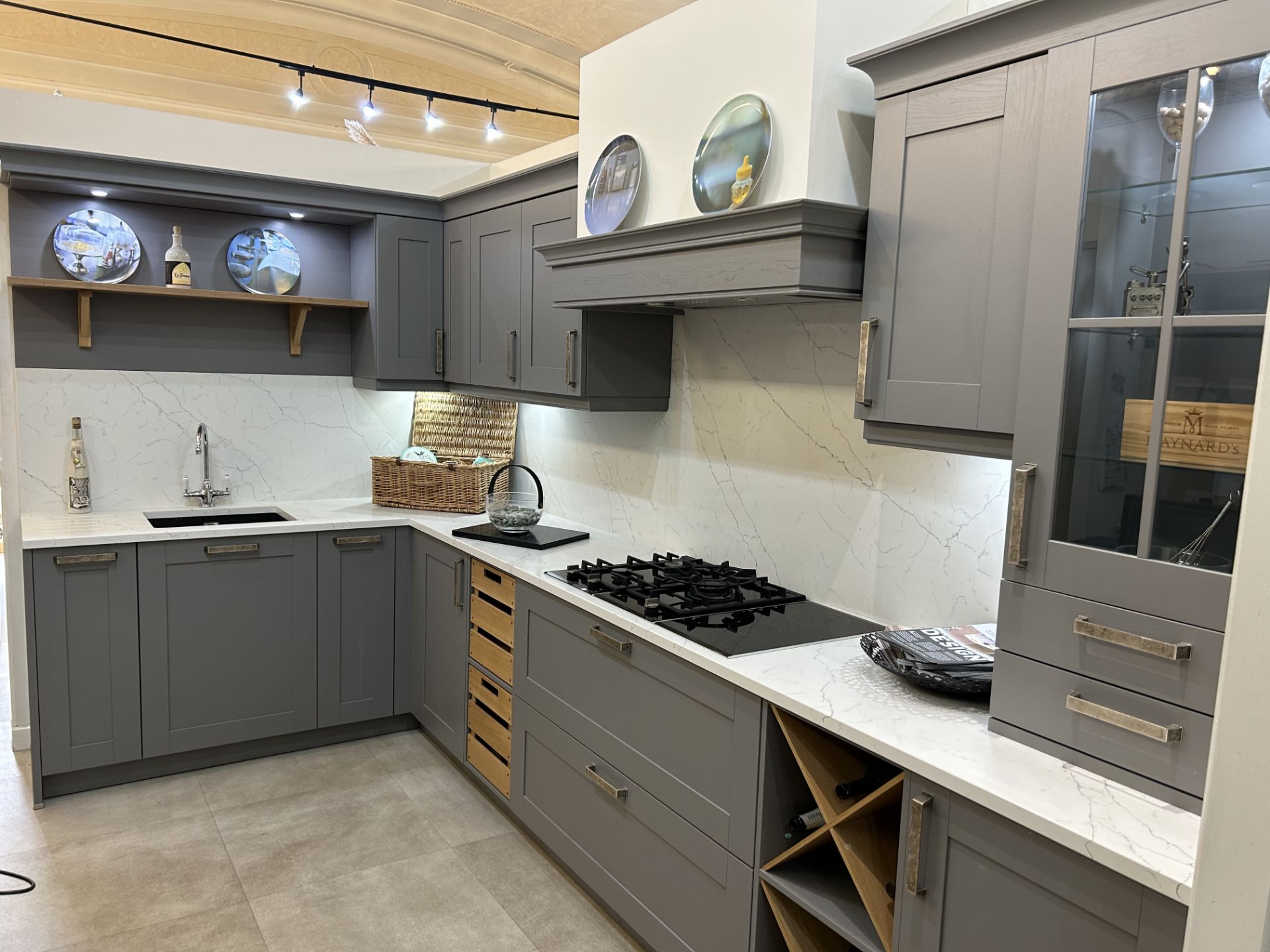 Display kitchen comprising grey laminated wood effect doors with metal handles