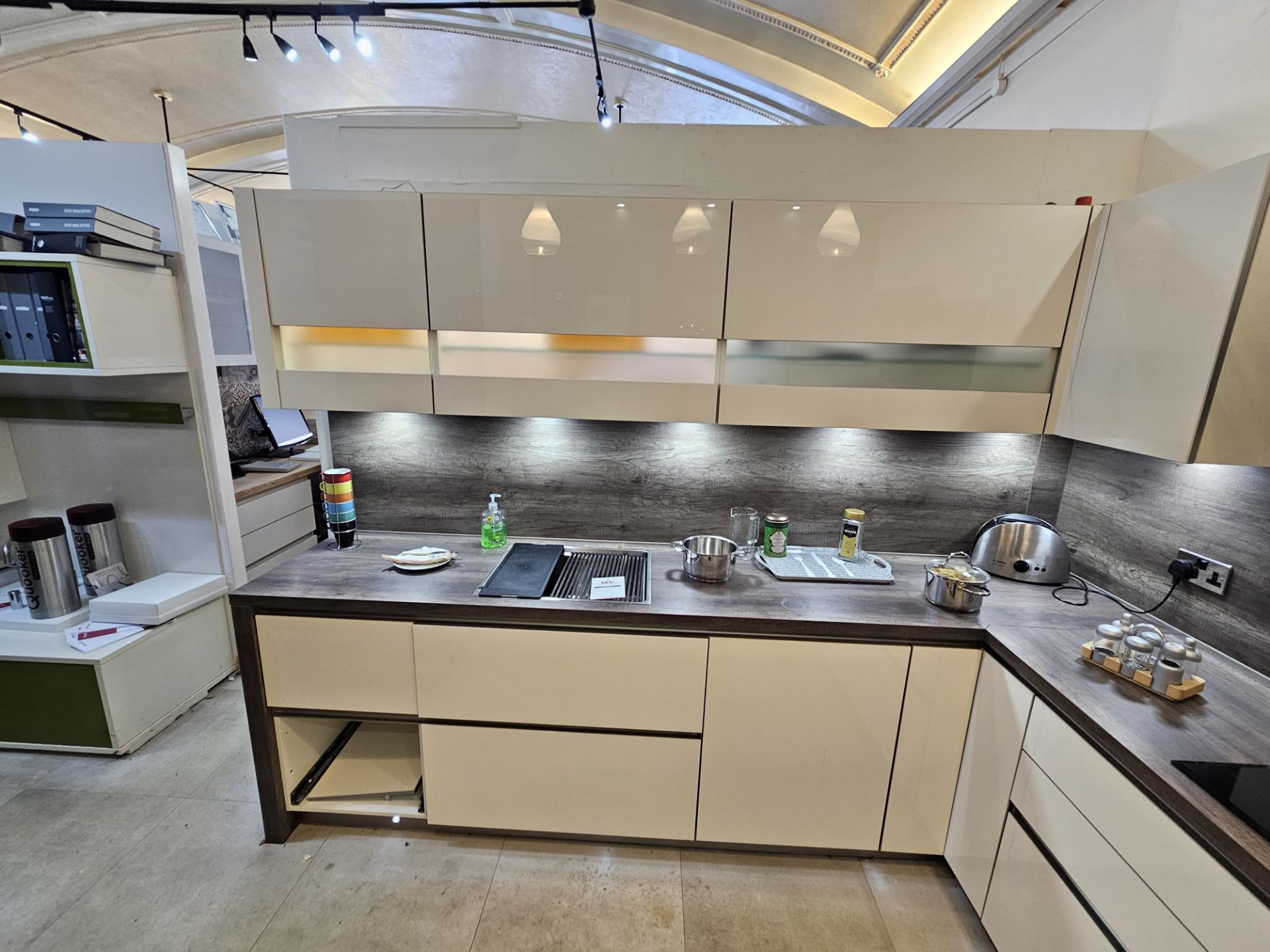 L' shape display kitchen comprising handleless acrylic cream doors, laminate surface and splashback