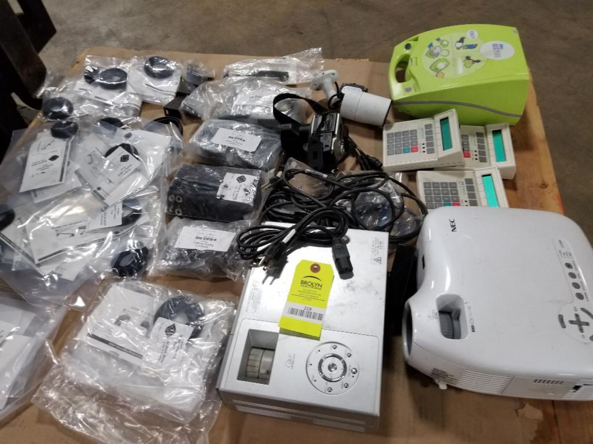 Pallet of assorted electrical. Projectors, calculators, defibrillator, camera.
