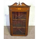 A George III style inlaid corner cabinet, with a ‘broken’ scrolled pediment over a single glazed