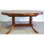 A modern Regency style oval extending dining table, the base with four curved and reeded legs, 154cm