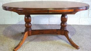 A modern Regency style oval extending dining table, the base with four curved and reeded legs, 154cm