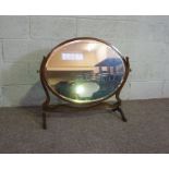 An Edwardian oval mirror on stand, with carved supports, 73cm high, 82cm wide; and another oval