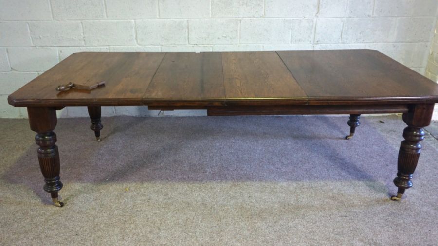 An Edwardian oak extending dining table, early 20th century, with a solid top, on four ring turned