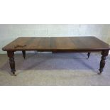 An Edwardian oak extending dining table, early 20th century, with a solid top, on four ring turned