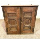 A small oak hanging cupboard, 17th century, with two fielded panelled doors, the interior with three