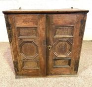 A small oak hanging cupboard, 17th century, with two fielded panelled doors, the interior with three
