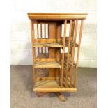 A vintage rotating bookstand, 20th century, of typical square form, with slatted supports and set on