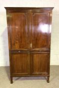 A Regency style double wardrobe, with two panelled doors, on tall tapered feet, 198cm high, 113cm
