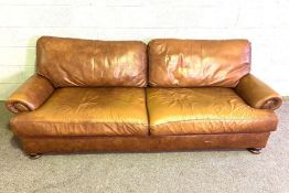 A vintage leather sofa, with long deep seat band brass hob-nailed scrolled ends, 230cm long