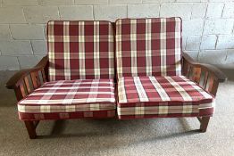 A modern teak framed adjustable two seat settee, with caned seat and red tartan cushions, 157cm