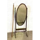 A Regency style mahogany cheval mirror, with oval plate, and sabre legs, with brass caps and