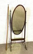 A Regency style mahogany cheval mirror, with oval plate, and sabre legs, with brass caps and