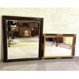 A large ebonized cushion framed wall mirror, with bevelled plate, late 19th century; together with