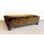 A large greeny brown 'velvet' covered ottoman, with cushioned top and nailed sides, on bun feet,